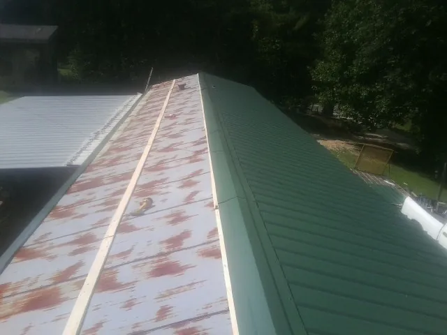 Old rusted panels beside newly installed green metal roofing — Wind Damage Roof Repair by Roofing Brothers in Mount Gretna