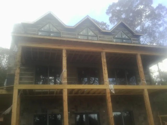 Dormers and porch framing on a large log home under construction — Roof Coating work by our crew in Mount Gretna