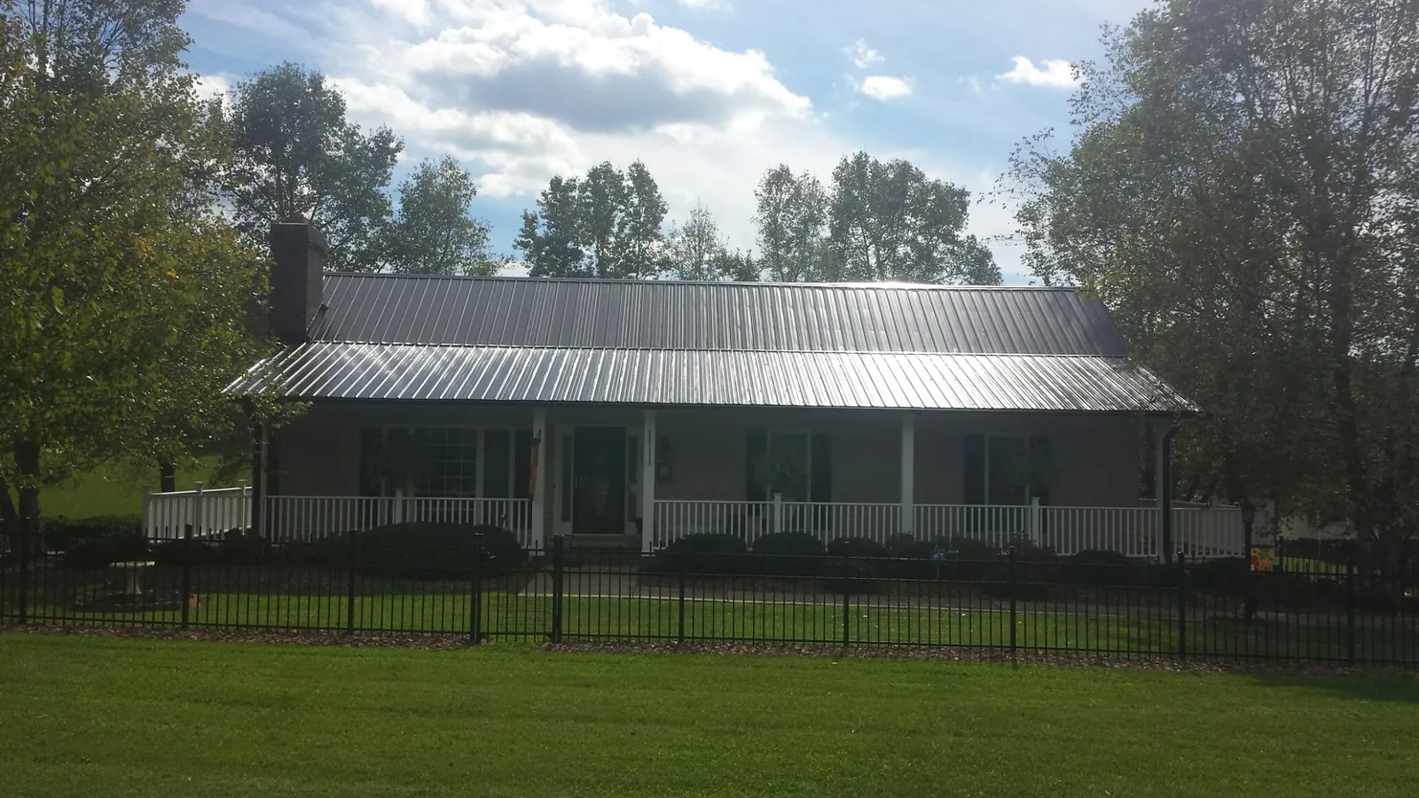 Gray metal roof on a brick ranch with a full width front porch — Gutter Guard Installation work by our crew in Mount Gretna