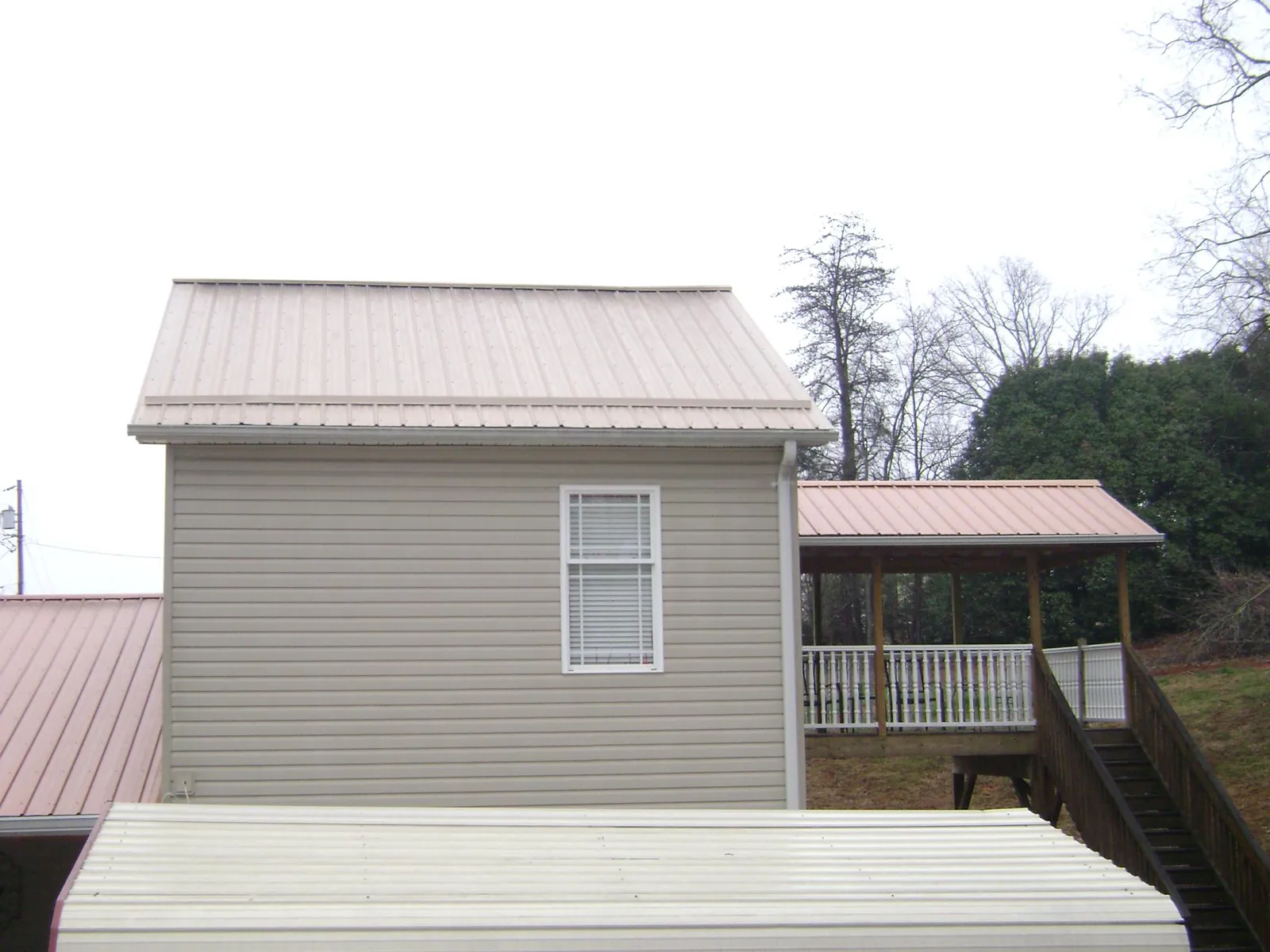 Tan metal roofs on a two story addition and attached porch, from a Roof Replacement job in Mount Gretna