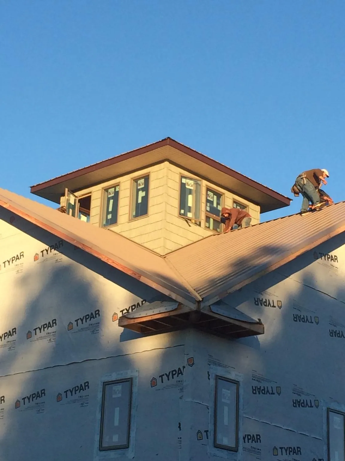 Roofers working around a rooftop cupola on a new metal roof at sunset — Roof Waterproofing in Mount Gretna by Roofing Brothers